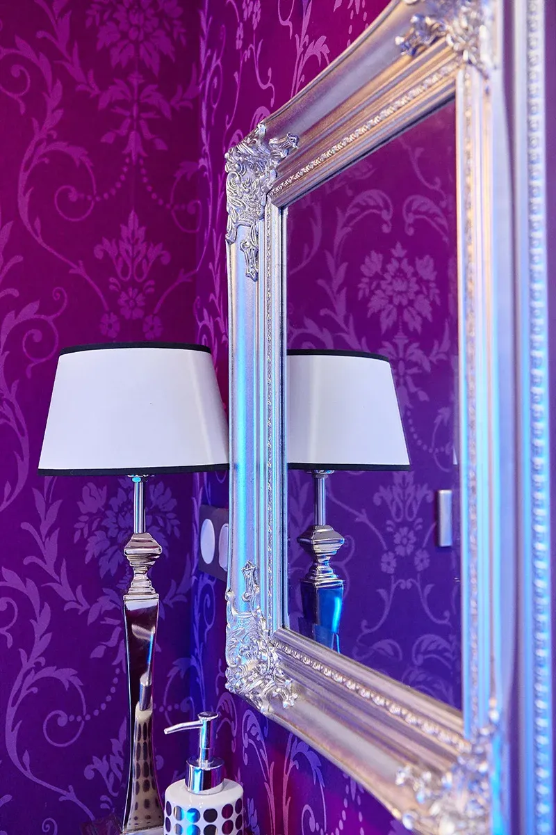 Un détail de la décoration de l'institut : miroir à cadre argenté sur papier peint baroque